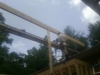 Carpenter setting a ridge beam over a new addition frame — Ice Dam Removal by Roofing Brothers in Rives Junction
