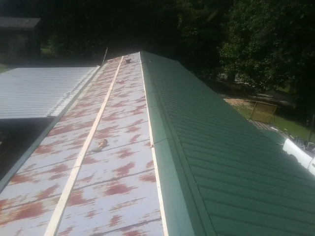 Old rusted panels beside newly installed green metal roofing — Wind Damage Roof Repair by Roofing Brothers in Rives Junction