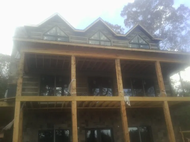 Dormers and porch framing on a large log home under construction — Roof Coating work by our crew in Rives Junction