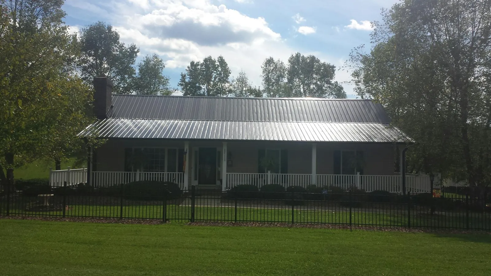 Gray metal roof on a brick ranch with a full width front porch — Gutter Guard Installation work by our crew in Rives Junction