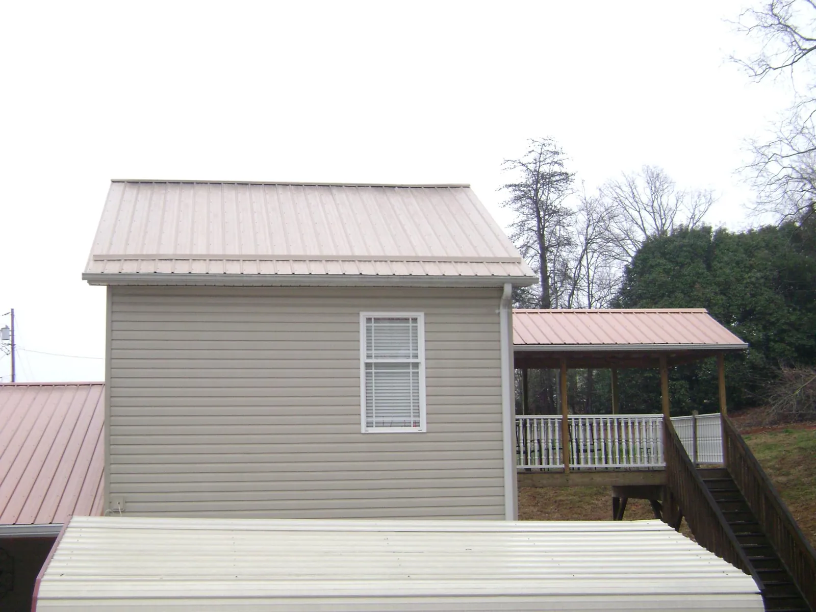 Tan metal roofs on a two story addition and attached porch, from a Roof Replacement job in Rives Junction
