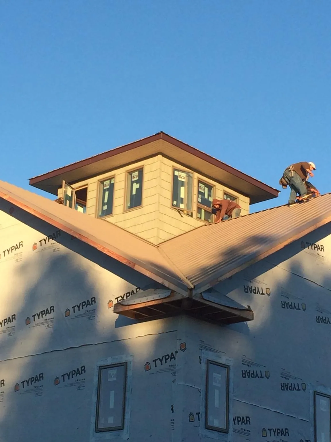 Roofers working around a rooftop cupola on a new metal roof at sunset — Roof Waterproofing in Rives Junction by Roofing Brothers